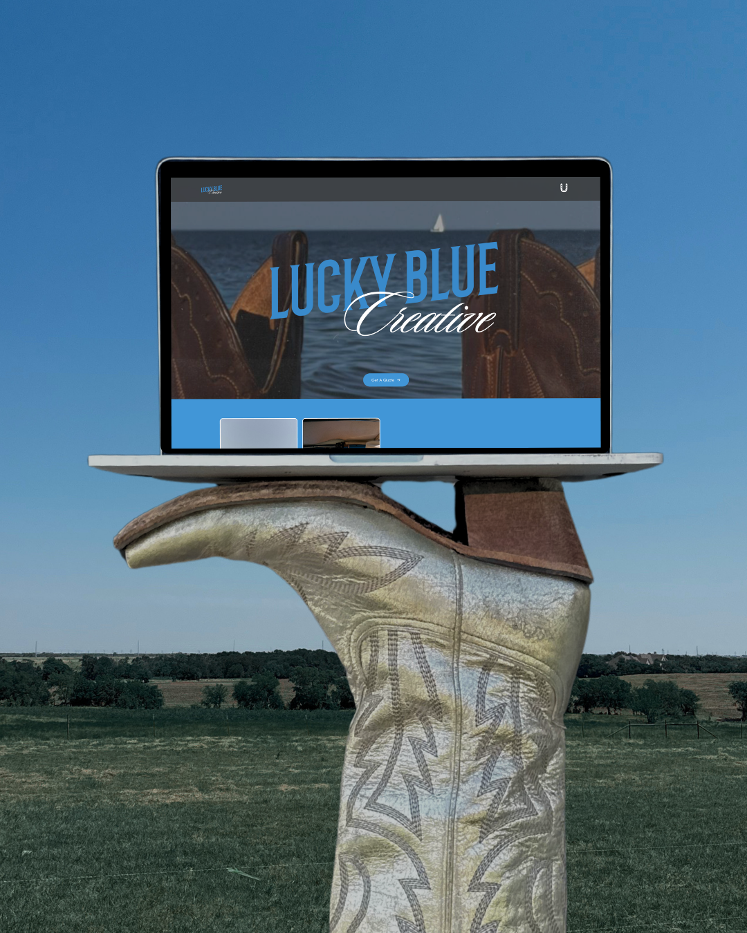 Laptop displaying the Lucky Blue Creative website, balanced on a cowboy boot in a pasture